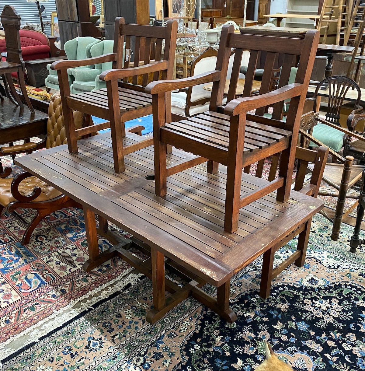 A rectangular stained teak slatted garden table, length 180cm, depth 90cm, height 70cm, together with a pair of teak garden benches, width 147cm and two garden elbow chairs